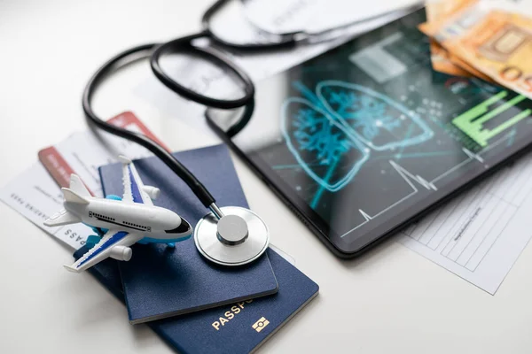 Modern social health insurance program. Tablet computer with healthcare application interface on screen. Stethoscope, x-ray image and cardiogram on wooden desk. Digital healthcare technologies