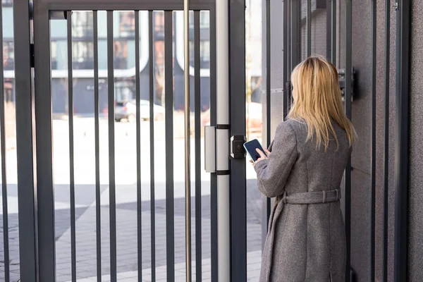 Mujer Rubia Pensativa Puerta Abierta Usando Teléfono Inteligente Con Aplicación —  Fotos de Stock