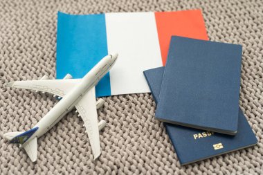 Flag of France with passport and toy airplane on wooden background. Flight travel concept