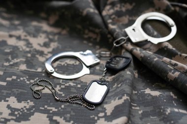 Askeri kamuflaj üniforması, arka planda kelepçeli.