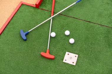 Sentetik çimlerin üzerinde golf topları olan renkli golf sopaları..