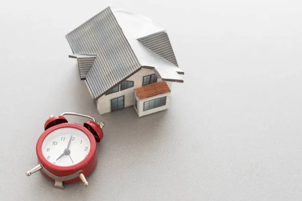 stock image House model with alarm clock on wooden background