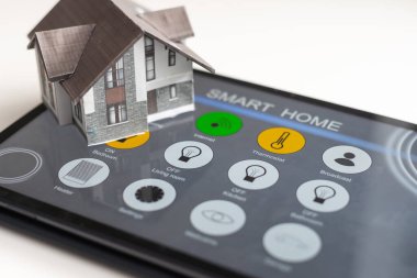 Küçük ev modeli tablet ve ev elektronik cihazları ile kablosuz bağlantı kuruyor. Akıllı ev kontrollü ve Otomasyon sistemi teknolojisi.