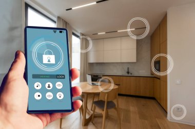 İnternet, akıllı ev, mutfak ve ağ bağlantısı konsepti. İnsan eli telefonu ve mutfak geçmişi bulanık olan güç kullanımını saymak için akıllı ev uygulaması..