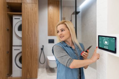 Oturma odasındaki duvara dijital dokunmatik ekran panelle evi kontrol etmek. Evdeki akıllı aygıtları yönetmek için akıllı ev ve mobil uygulama kavramı