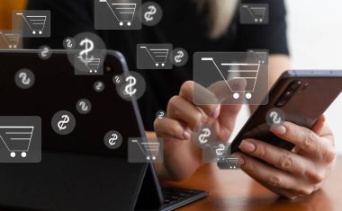 Çevrimiçi alışveriş ve e-ticaret kavramı. Alışveriş arabası simgesi olan dizüstü bilgisayar kullanan genç bir kadın, çevrimiçi mağazadan sipariş veren, internetten alışveriş yapan, klavyede yazı yazan sanal ekranda konsept kullanan bir kadın.