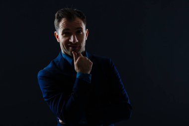 Portrait shot of a middle aged businessman wearing suit while standing at dark background