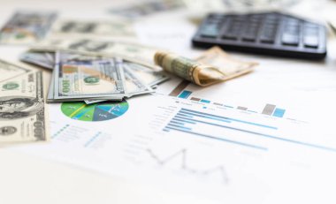 İşletme grafiği kağıt kalem hesap makinesi ofis masasında bir dolar. Mali raporlar kontrol ediliyor