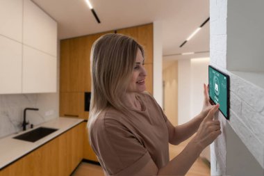 Akıllı ev sistemini kullanan ya da evden çıkmadan önce modern alarm sistemini çalıştıran hoş bir kadın. Mutlu kadın eve ya da daireye döndüğünde kolay güvenlik teknolojisini kapatıyor..