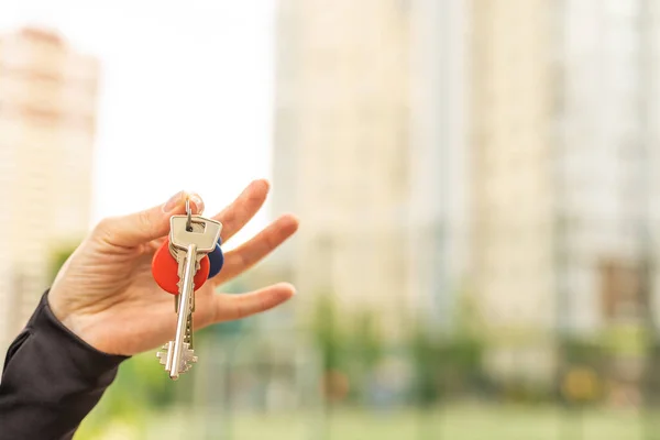 stock image Close up of hands of young woman holding house keys of her new house. Woman hand holding housekey shaped keychain. Girl buying new home for her family and showing key with copy space