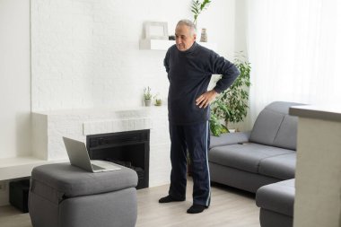 Online workout. elderly man doing exercise with online tutorial at home, panorama, free space.