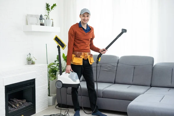 Dry cleaning worker removing dirt from sofa indoors.