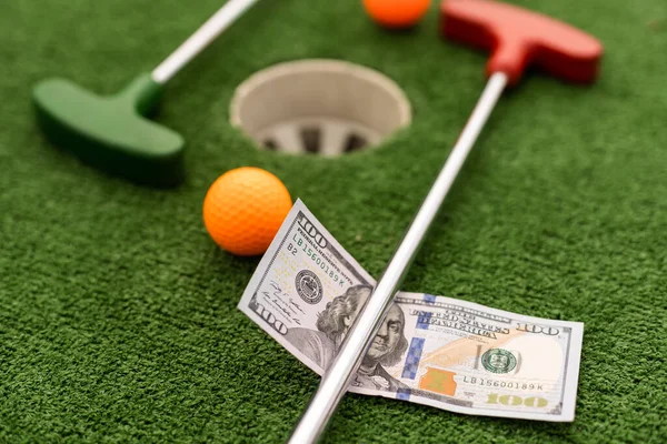 Money, mini golf balls on grass. Concept of sports bet.