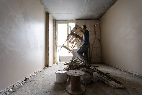 Construction worker wearing worker overall with wall plastering tools renovating apartment house. Plasterer renovating indoor walls and ceilings with float and plaster. Construction finishing works