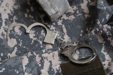 Kamuflaj geçmişinde kelepçe. Metal prangalar izole edildi. Hukuk. Sınırlama. Özgürlük için. - Güvenlik. Polis bilezikleri. Askeri üniforma. Asker tekstil ürünleri. Beneklerin dokusu. Kamuflaj renkleri
