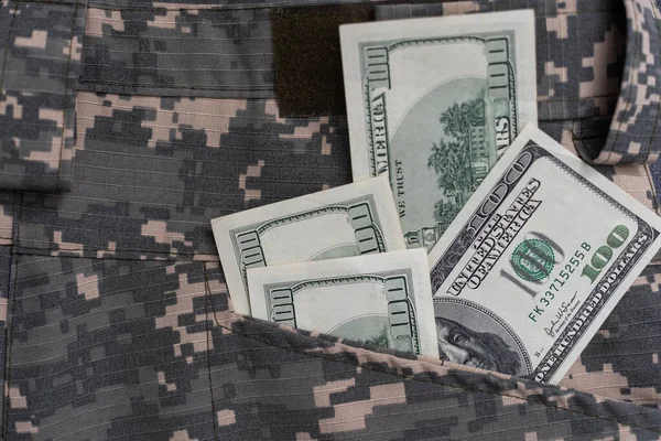 stock image US dollar bills on fabric with texture of Ukrainian military pixeled camouflage. Cloth with camo pattern in grey, brown and green pixel shapes. Official uniform of Ukrainian soldiers close up