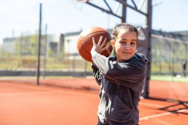 Şehrin arka planında basketbol topu olan bir kız. Sokak basketbolu