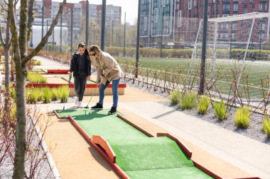 Anne ve kızı şehirde birlikte mini golf oynuyorlar.