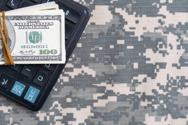 Ukrayna askeri kamuflajlı kumaş dokusuna Amerikan Doları banknotları. Gri, kahverengi ve yeşil pikselli kamuflaj desenli kumaş. Ukrayna askerlerinin resmi üniforması yaklaşıyor.