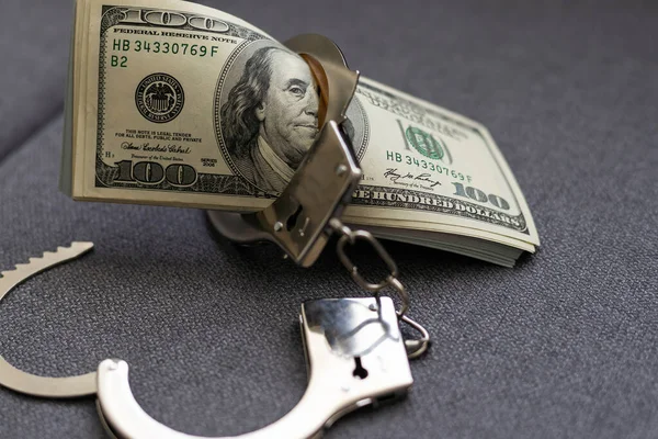 The handcuffs are on hundred-dollar bills. Power and bribery. Criminal ransom. Criminal earnings. Business concept. The concept of wealth. High quality photo