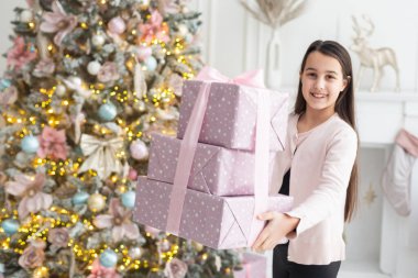 Elinde hediye tutan çok güzel bir kız. Noel havası. Çocuk mutlu bir gülümseme ile hediye verir. Mesaj için yer. Bokeh çelenkleri. Yeni Yıl.