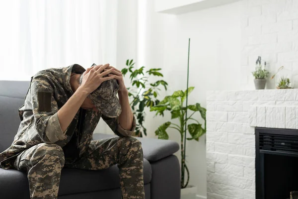 A man in a military uniform is sitting in a chair by the window. Concept: a soldier at a psychologists appointment, post-traumatic stress syndrome, mental disorder, the consequences of war.