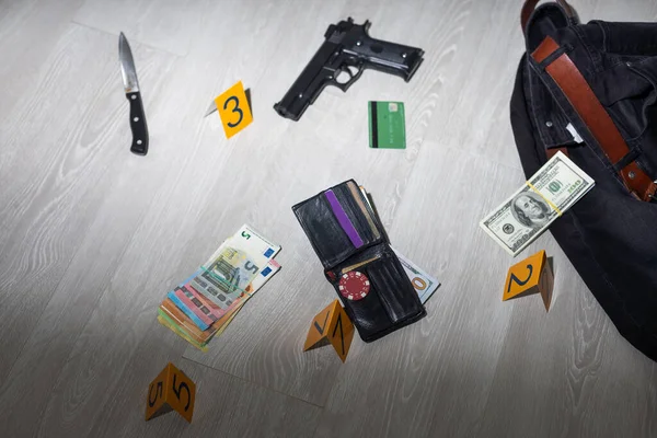 Crime scene investigation - numbering of evidences after the murdering in apartment. Brass knuckle, wallet and clothes with evidence markers. High quality photo