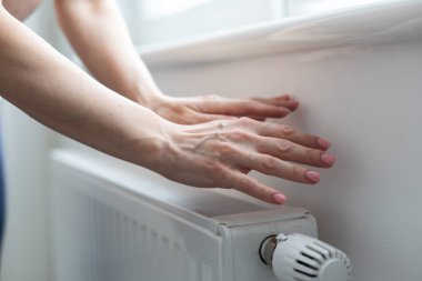 Bir kadın eli ısıtma termostatının sapını tutar. Isıtma hizmeti maliyeti konsepti, kamu maliyeti zammı. Yüksek kalite fotoğraf