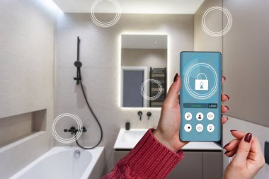 Akıllı ev teknolojisi, akıllı telefon uygulamasındaki IoT İnternet arayüzü modern apartman içindeki nesnelere bağlı ekran, uzaktan kumanda olarak kadın tutucu aygıtı.