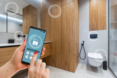 Akıllı ev, ev otomasyonu, uygulama simgeli aygıt. Kadın akıllı telefonunu akıllı güvenlik uygulaması ile evinin kapısını açmak için kullanıyor.
