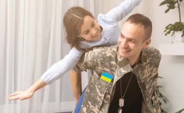 Ukrayna askeri üniformalı asker kızına sarılıyor. Aile toplantısı.