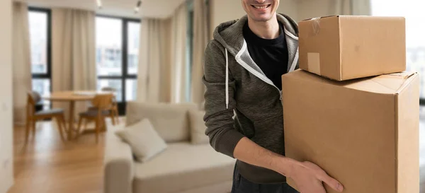 Man lifting cardboard boxes in apartment interior