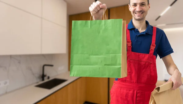 一个微笑的送货员手里拿着纸袋和食品容器 食肆的优质服务 — 图库照片
