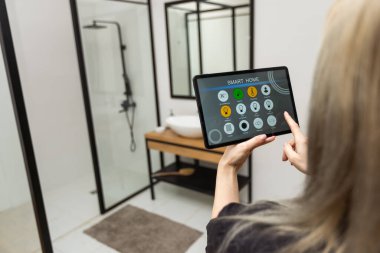 Female hands holding digital tablet with smart home app.