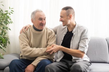 Help needed. Pleasant senior man sitting on the sofa.