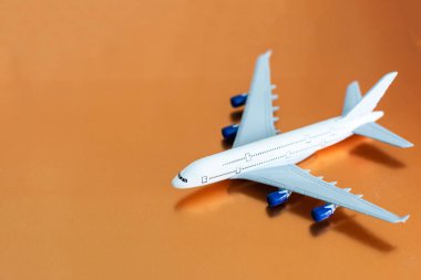 Turuncu arka planda uçak, düz yatış, seyahat konsepti.