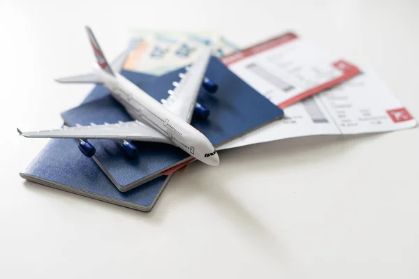 Toy airplane and passport with tickets on white background, top view.