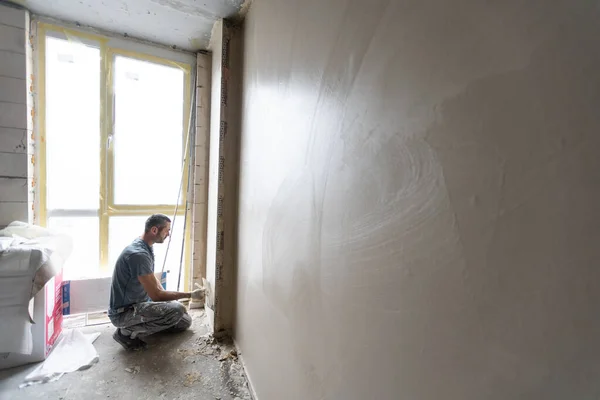 トロウエルと仕事をしている男の左官建設労働者は壁を漆喰で塗り — ストック写真