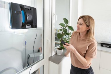 Pencereleri temizleyen kadın robot temizleyicisiyle
