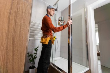 Tesisatçı banyoya duş kabini kuruyor..