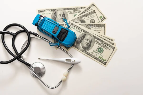 Emergency diagnostics. High prices for ambulance services. white car on stack of dollars next to red question mark and stethoscope.