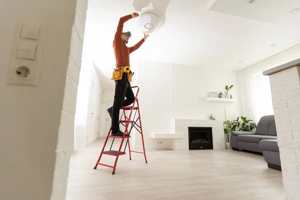 Electrician worker installation electric lamps light inside apartment. Construction decoration concept
