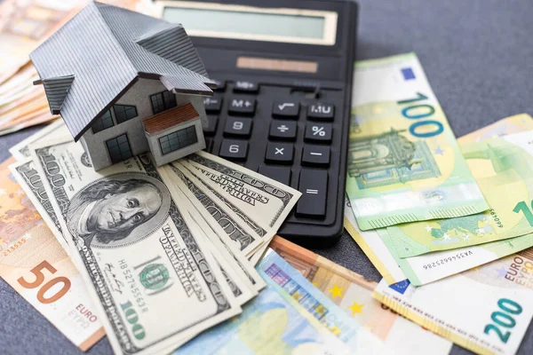 The concept of mortgage and rental housing and real estate. Mortgage credit lending. House of euro bills on the plan of the house and laid out dollar banknotes on a blue background. High quality photo