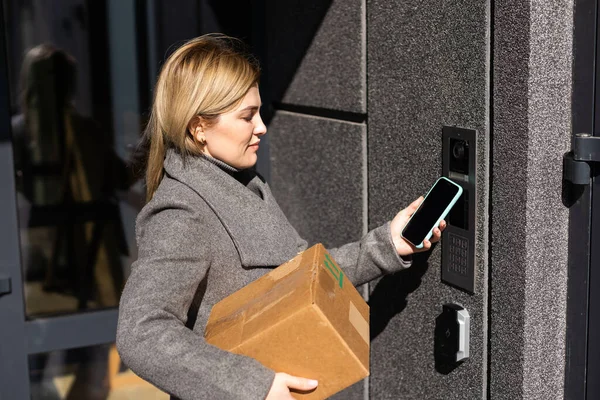 Pensive Ξανθιά Γυναίκα Ανοιχτή Πόρτα Χρησιμοποιώντας Smartphone Εφαρμογή Mock Οθόνη — Φωτογραφία Αρχείου
