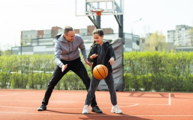 Baba ve kızı sokakta basketbol oynarken.