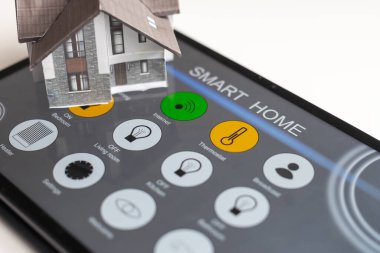 Küçük ev modeli tablet ve ev elektronik cihazları ile kablosuz bağlantı kuruyor. Akıllı ev kontrollü ve Otomasyon sistemi teknolojisi.