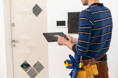bir elektrikçi tabletle bir dahili telefonu tamir eder.