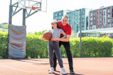 Baba ve kızı birlikte sahada basketbol.