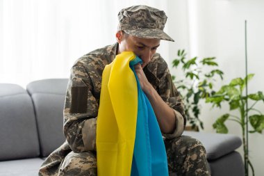 Beyaz arka planda sarı ve mavi bir bayrak taşıyan askeri üniformalı Ukraynalı vatansever asker.