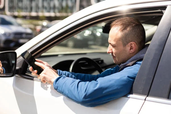 驾驶智能手机的人开着车 显示出智能手机显示出快乐的笑容 男性司机使用显示空白屏幕的应用程序坐在司机座位上 — 图库照片